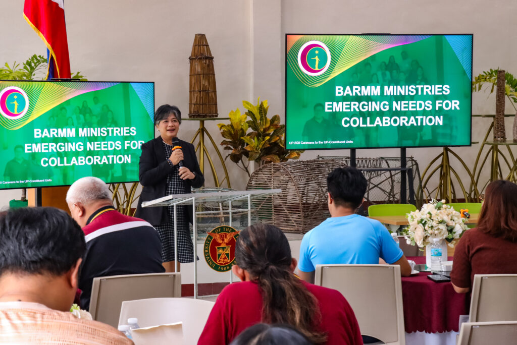 A woman stands at a podium speaking into a microphone, with display screens beside her reading "BARMM MINISTRIES EMERGING NEEDS FOR COLLABORATION."